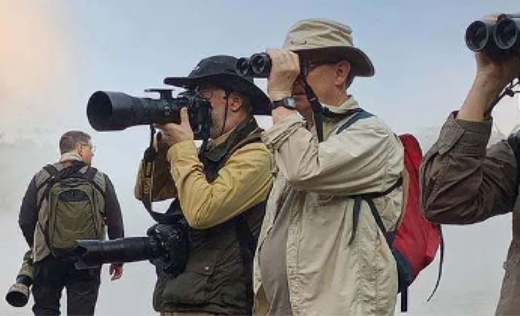 Birdwatchers on a Luxury Uganda Birding Safari using binoculars and cameras to observe rare bird species across Uganda’s premier birding destinations