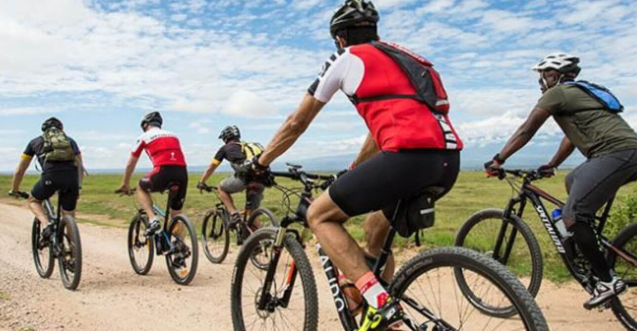 Cyclists riding along a scenic dirt road during an adventure experience in Uganda
