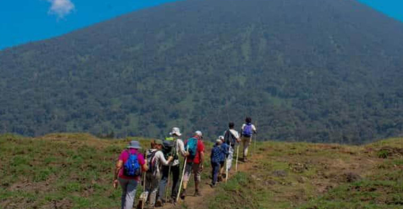 Nature Experiences in Uganda and Rwanda with hikers approaching a volcanic mountain