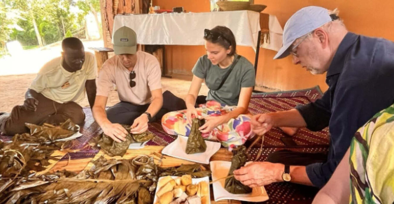 Cultural experience in Uganda with visitors sharing traditional food with a local community