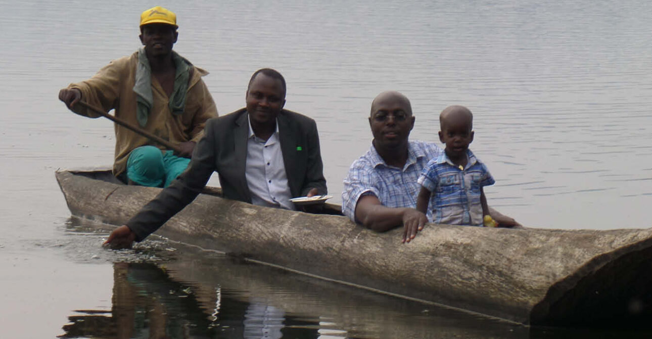 Passengers travelling in a traditional wooden dugout canoe on Lake Bunyonyi, Uganda, accompanied by a local canoe guide.