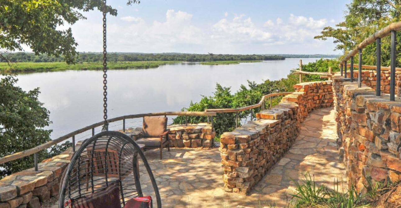 Luxury Safaris in Uganda and Rwanda featuring a scenic riverside lodge terrace with comfortable seating and panoramic water views.