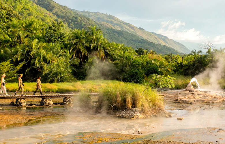 Safari packages in Uganda featuring a guided walk through a natural hot spring landscape.