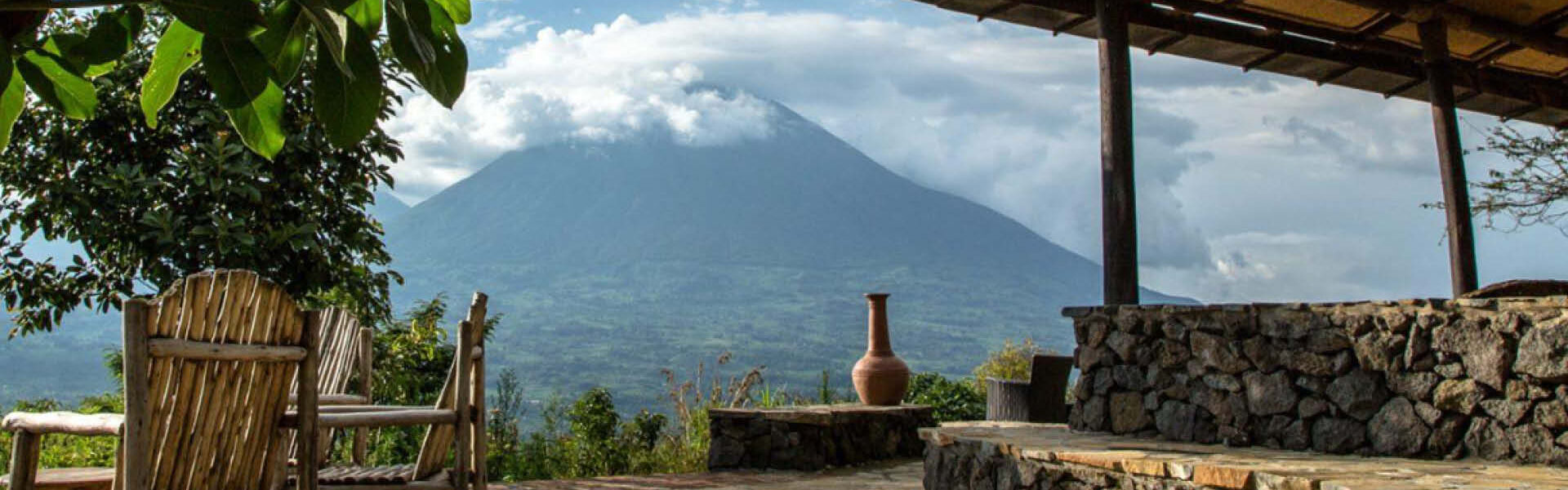 Rustic safari lodge terrace overlooking a volcanic mountain in Rwanda.