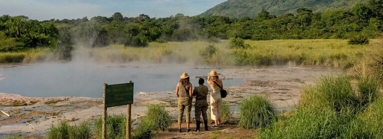 Visitors accompanied by a ranger viewing the steaming Sempaya Hot Springs in Semuliki National Park, Uganda.