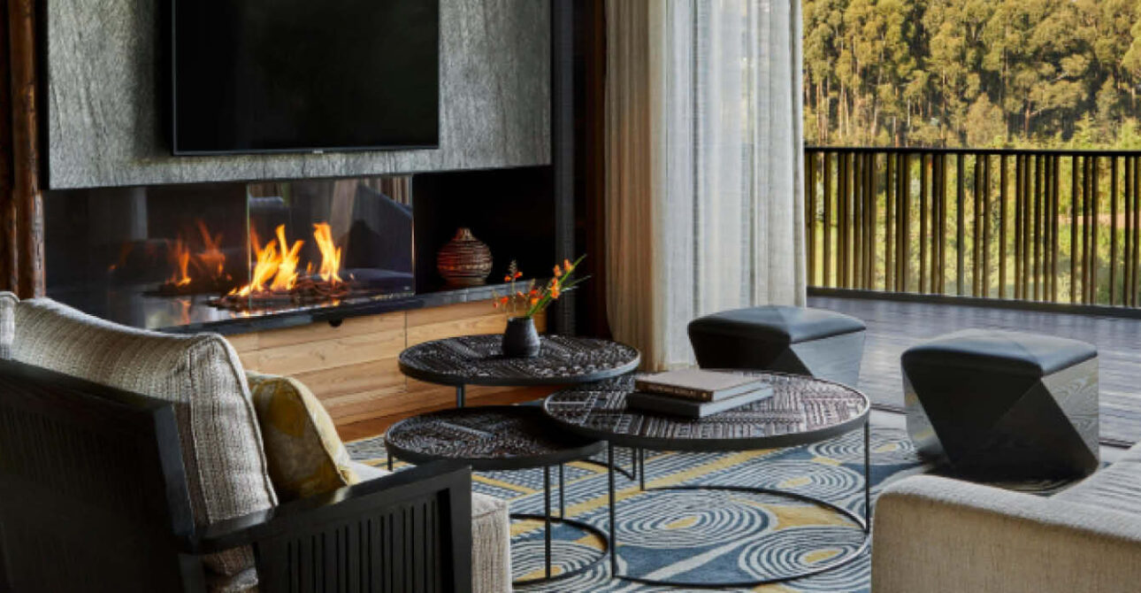 Elegant Signature safari accommodation lounge at One&Only Gorilla's Nest in Rwanda, featuring a fireplace, comfortable seating and forest views.